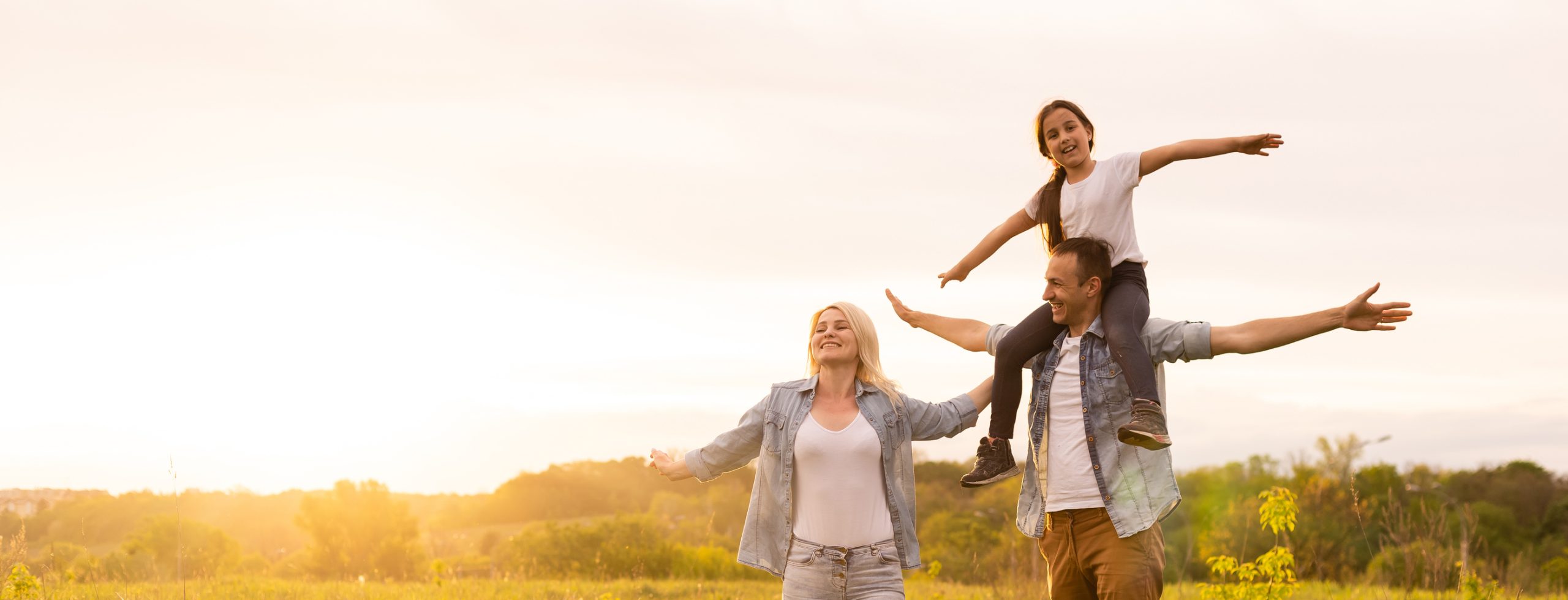 Smiling family standing together in a field at sunset
