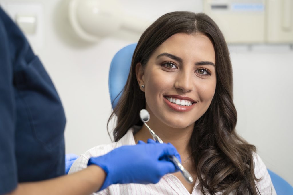 Female sitting in the dental chair with a dental instrument
