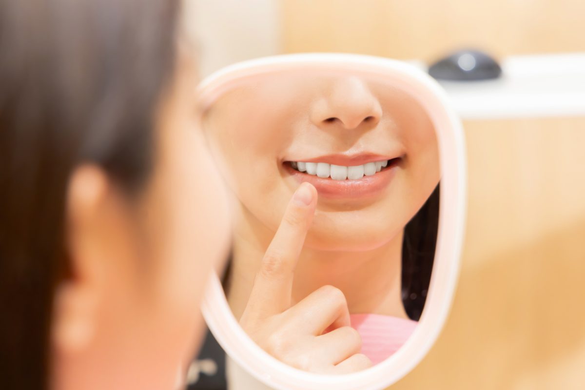 woman looking at her smile in a mirror